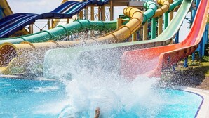 Un parque acuático con piscina, toboganes de agua y una persona nadando.