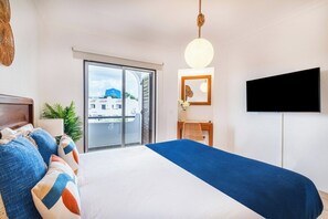 Ein Hotelzimmer mit einem Bett, einem Fernseher, einem Schreibtisch und Blick auf Gebäude durch eine Schiebetür.