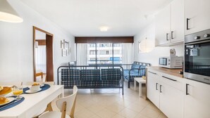Eine moderne Küche mit Essbereich, einer Couch und Blick ins Freie.
