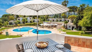 Une terrasse sur le toit avec une piscine, un espace aménagé pour les repas et des bâtiments environnants.