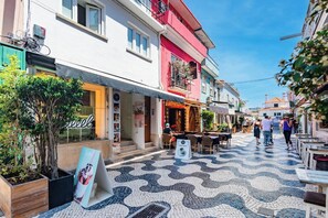 Eine Straße mit Geschäften, Außenplätzen und einem Kachelbelag.