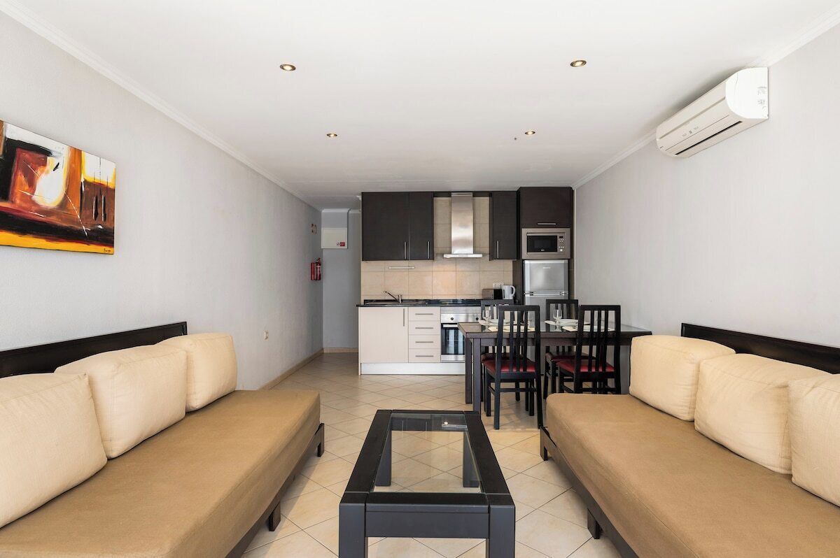 A modern living room with a sofa, a coffee table, and a dining area with chairs and a table.
