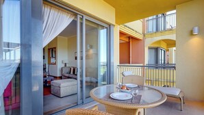 A balcony with wicker furniture, a glass table, and a view of the interior. - The Prestige @ The Vilamoura Residences (Quarteira)