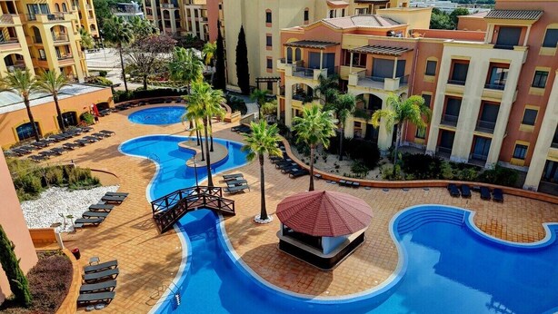 A resort with a large swimming pool, sun loungers, and palm trees. - The Prestige @ The Vilamoura Residences (Quarteira)