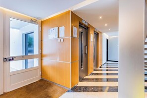 Ein moderner Hotelkorridor mit Holzvertäfelung, Aufzügen und einer Rezeption.