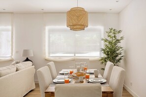 Ein Essbereich mit einem für das Frühstück gedeckten Tisch, einer Rattan-Pendelleuchte und einer Bambuspflanze.