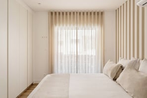 Ein Schlafzimmer mit Bett, Vorhängen und einer gestreiften Wand.