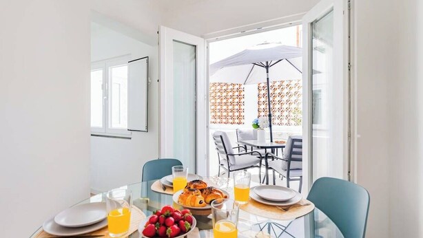 Una mesa de desayuno con platos, vasos y una cesta de frutas.