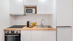 Una cocina moderna con armarios blancos, un microondas, un fregadero y un horno empotrado.