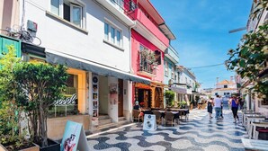 Una calle con tiendas, mesas al aire libre y adoquinado.