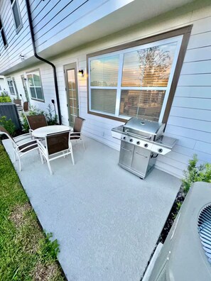 Eine Terrasse im Freien mit Grill, Stühlen und Tisch.