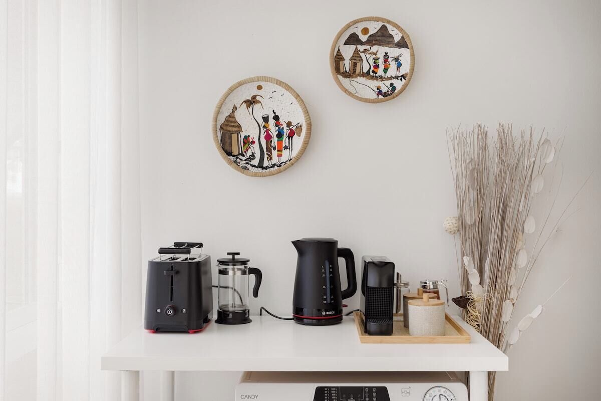 A kitchen counter with a toaster, coffee maker, and kettle. There are decorative plates on the wall above.