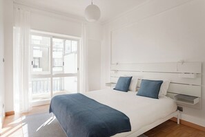 Ein modernes Schlafzimmer mit einem großen Bett, einem Nachttisch und Blick ins Freie.