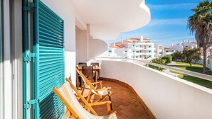 Ein Balkon mit Blick auf weiße Gebäude, eine Palme und einer Hängematte.