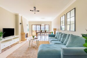 Ein Wohnzimmer mit einer Couch, einem Fernseher und einem Essbereich mit Stühlen und einem Tisch.
