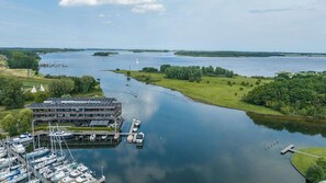Un puerto deportivo con barcos amarrados, un edificio de techo plano y un río tranquilo.