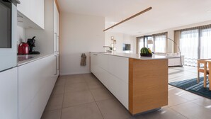 Eine moderne Küche mit weißen Schränken, einer Holztischinsel und einem roten Wasserkocher.