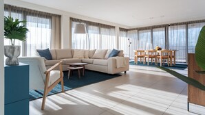Ein modernes Wohnzimmer mit einem beigefarbenen Ecksofa, einem Holztisch und einem Essbereich mit Holztisch und Stühlen.