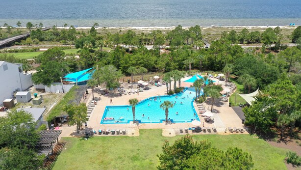 Un complexe hôtelier doté d’une grande piscine, d’un accès à la plage et d’une végétation luxuriante.