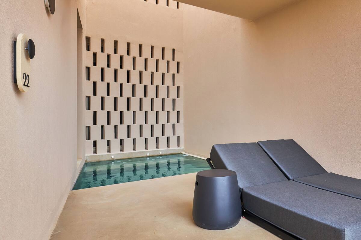 Un espacio de spa con piscina, sillón de masajes y pared con diseño geométrico.