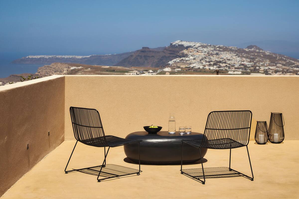Una terraza con dos sillas, una mesa redonda y dos jarrones.