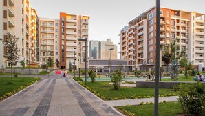 Un immeuble résidentiel à plusieurs étages, doté de balcons et d’une cour intérieure agrémentée de verdure.