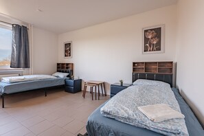 Une chambre avec deux lits, une petite table et une fenêtre avec des rideaux.