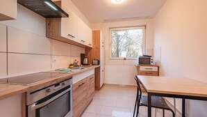 A modern kitchen with stainless steel appliances, wooden cabinetry, and a large window providing natural light. - Apartment 'Mk  Delmenhorst 9' with Wi-Fi (Delmenhorst)