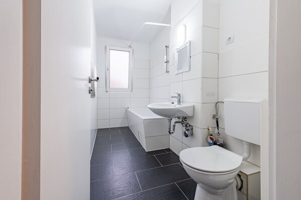 A modern bathroom with a bathtub, sink, and toilet.