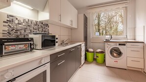 Une cuisine moderne équipée d’un four à micro-ondes, d’un grille-pain, d’un évier et d’un lave-linge.