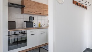 Una cocina moderna con armarios blancos, encimera de madera, estufa, microondas y cafetera.