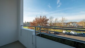 Un balcón con vistas a un estacionamiento y casas.