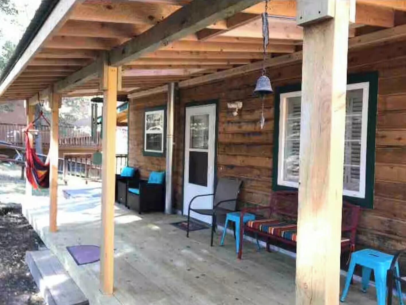 Una baita di legno con veranda, posti a sedere all'aperto e un'amaca.
