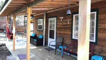 Una baita di legno con veranda, posti a sedere all'aperto e un'amaca.