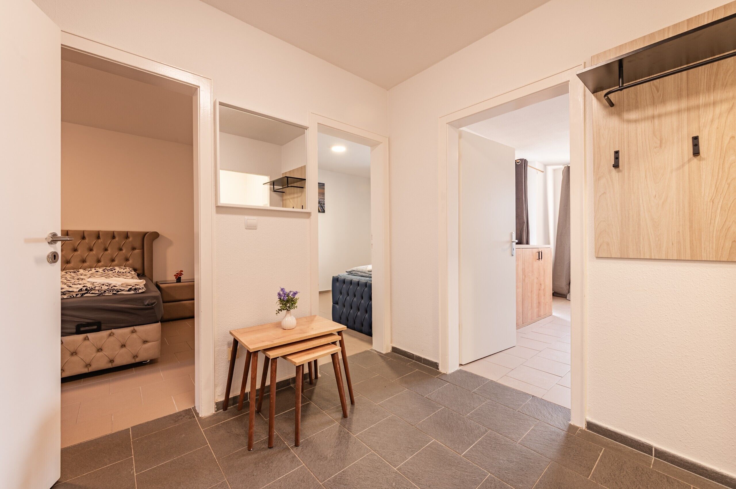 A modern interior with a bed, a small table with a vase, and a wardrobe.