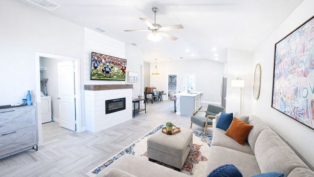 A spacious living room with a fireplace, a dining area, and a kitchen in the background. - Urban Cowboy | South Lubbock Retreat • Patio TV (Lubbock)