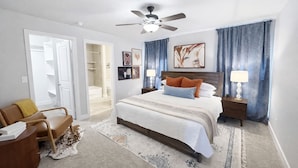 A hotel room with a bed, a desk, a chair, a ceiling fan, and a bathroom visible through an open door. - Urban Cowboy | South Lubbock Retreat • Patio TV (Lubbock)