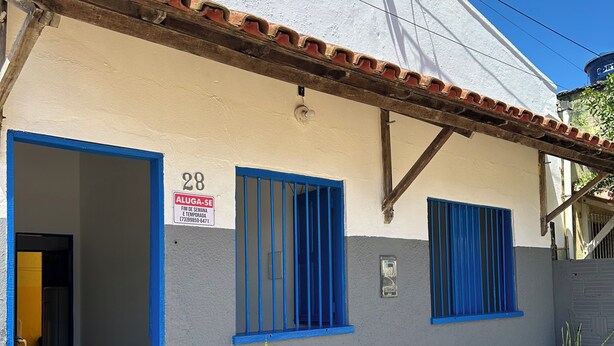 A building with a blue door and windows, a sign indicating a rental price, and potted plants outside. - Cozy little beach house, perfect for family and friends. (Alcobaça)