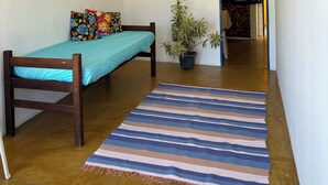 A small, single-room apartment with a bed, a potted plant, and a striped rug. - Cozy little beach house, perfect for family and friends. (Alcobaça)