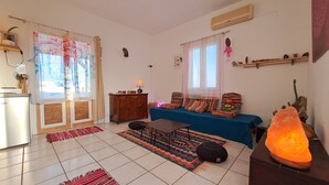 Een woonkamer met een bank, salontafel, lamp, verwarming en een raam met gordijnen.