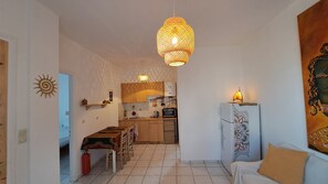 Un espace de vie compact comprenant un coin cuisine, un coin repas et un canapé.
