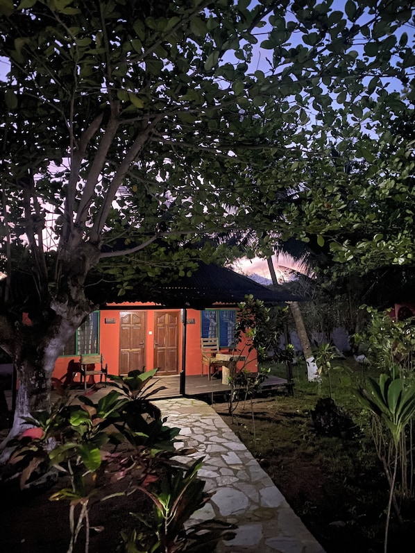 Un patio con un camino de piedra que lleva a un edificio de fachada roja y puertas de madera.