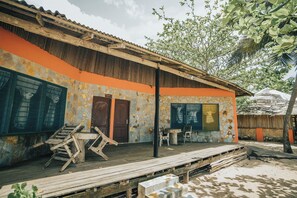 Un edificio rústico con fachada de piedra, terraza de madera y zona de estar al aire libre cubierta.