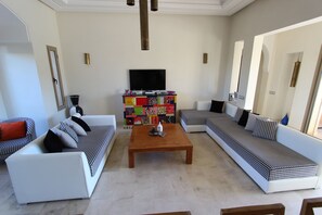 A living room with a sofa set, a coffee table, a TV, and a colorful cabinet. - Exceptional villa with private pool in Marrakech, Palmeraie area, Atlas view (Marrakech)