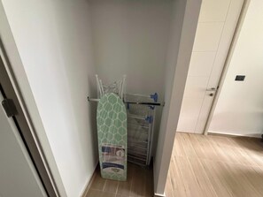 Ein schmaler Flur mit einer Tür rechts und einem Wandtrockner mit gemustertem Stoff.