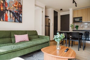 Una sala de estar moderna con un sofá verde, una mesa de centro redonda de madera y un cuadro en la pared.