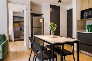 Una cocina moderna con refrigerador integrado, una mesa de comedor con sillas y un florero con flores sobre la mesa.