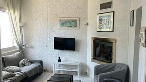 A modern living room with a sofa, a black ottoman, a white TV stand, and artwork on the walls. - Beach house at the foot of the Dunes (Seignosse)