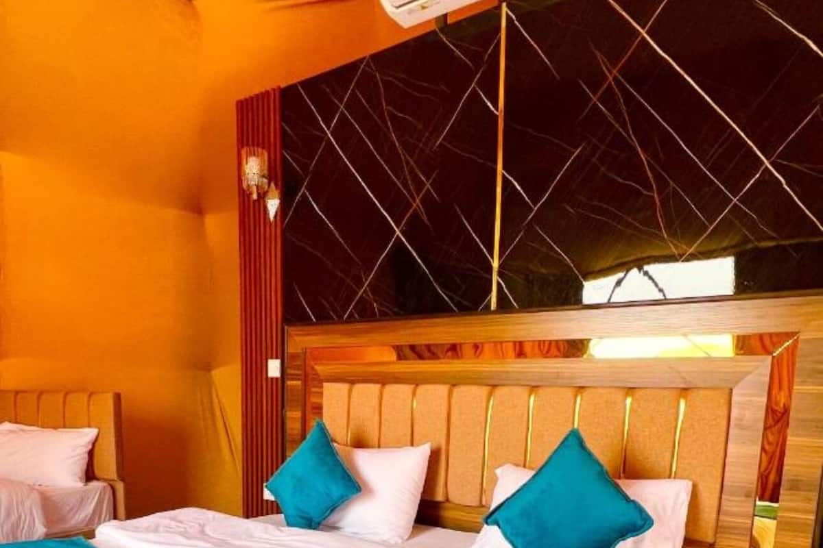 A double bed with a wooden headboard, two pillows, and a teal throw blanket.