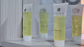 Drei Flaschen PURE Shampoo auf einem Regal.
